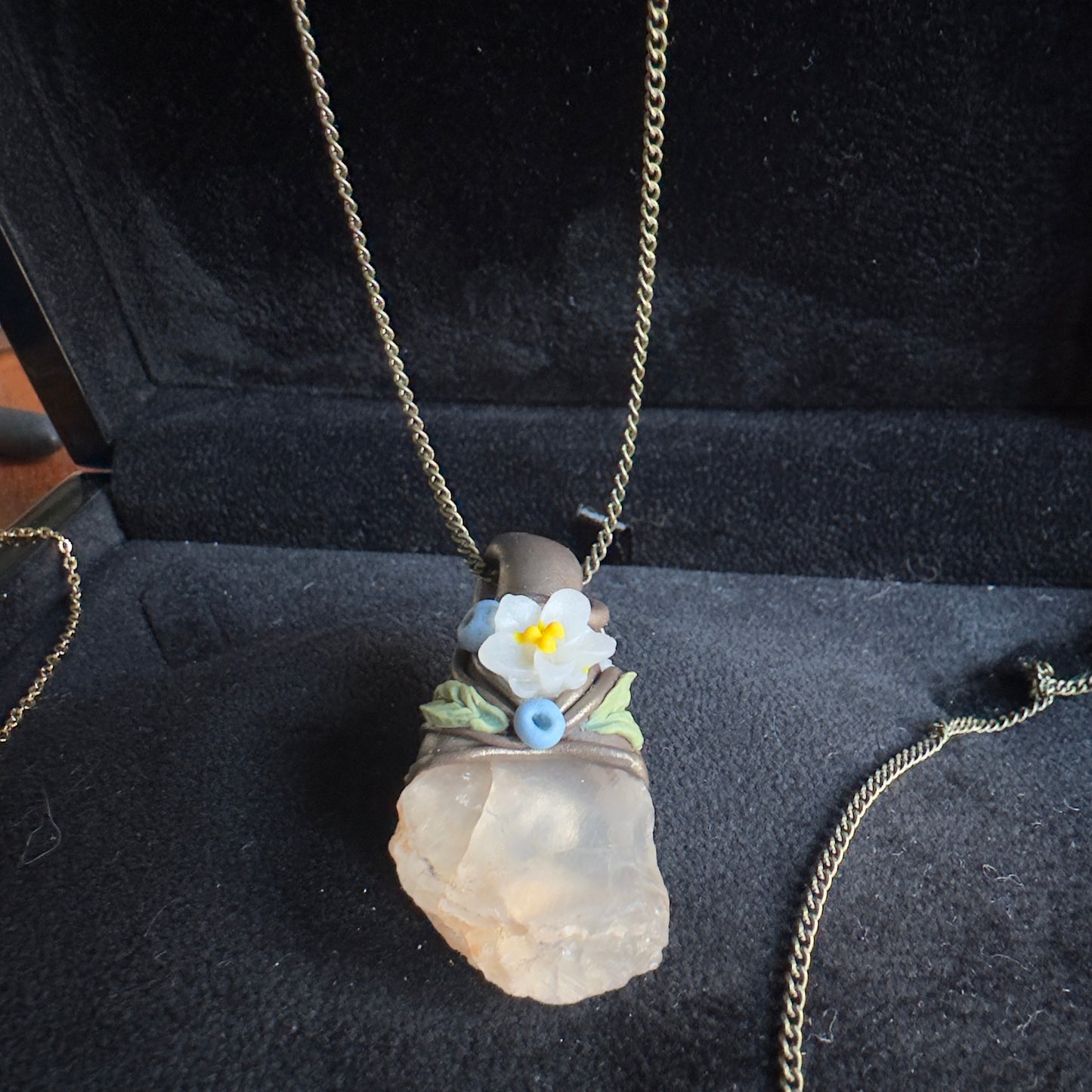 Kalnu kristāla amulets ar brūnu apdari un vienu ziediņu